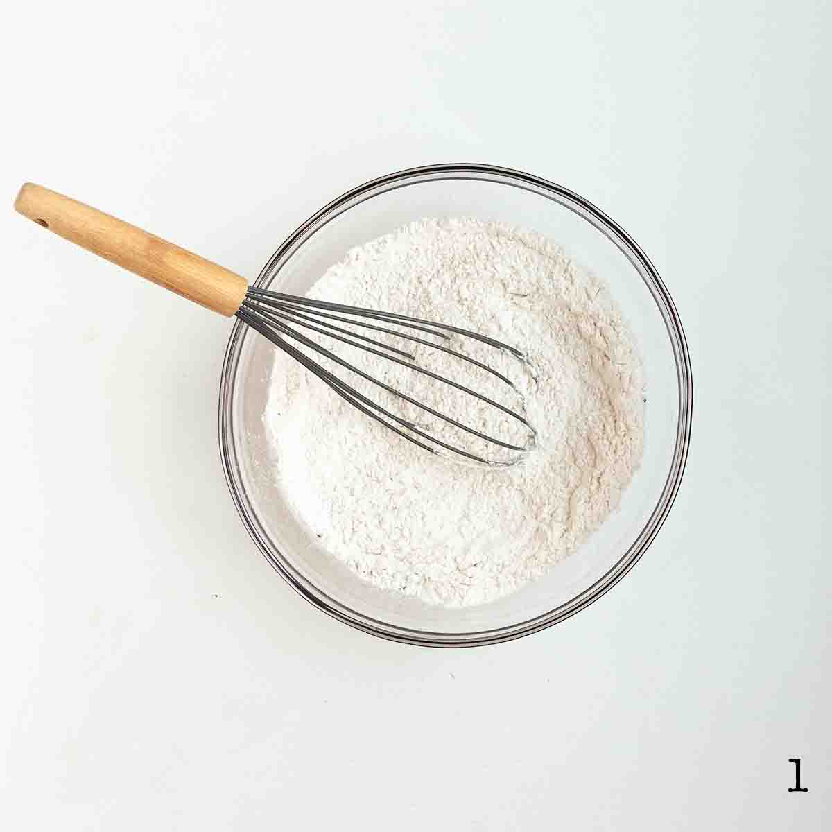 A whisk in a bowl of flour.