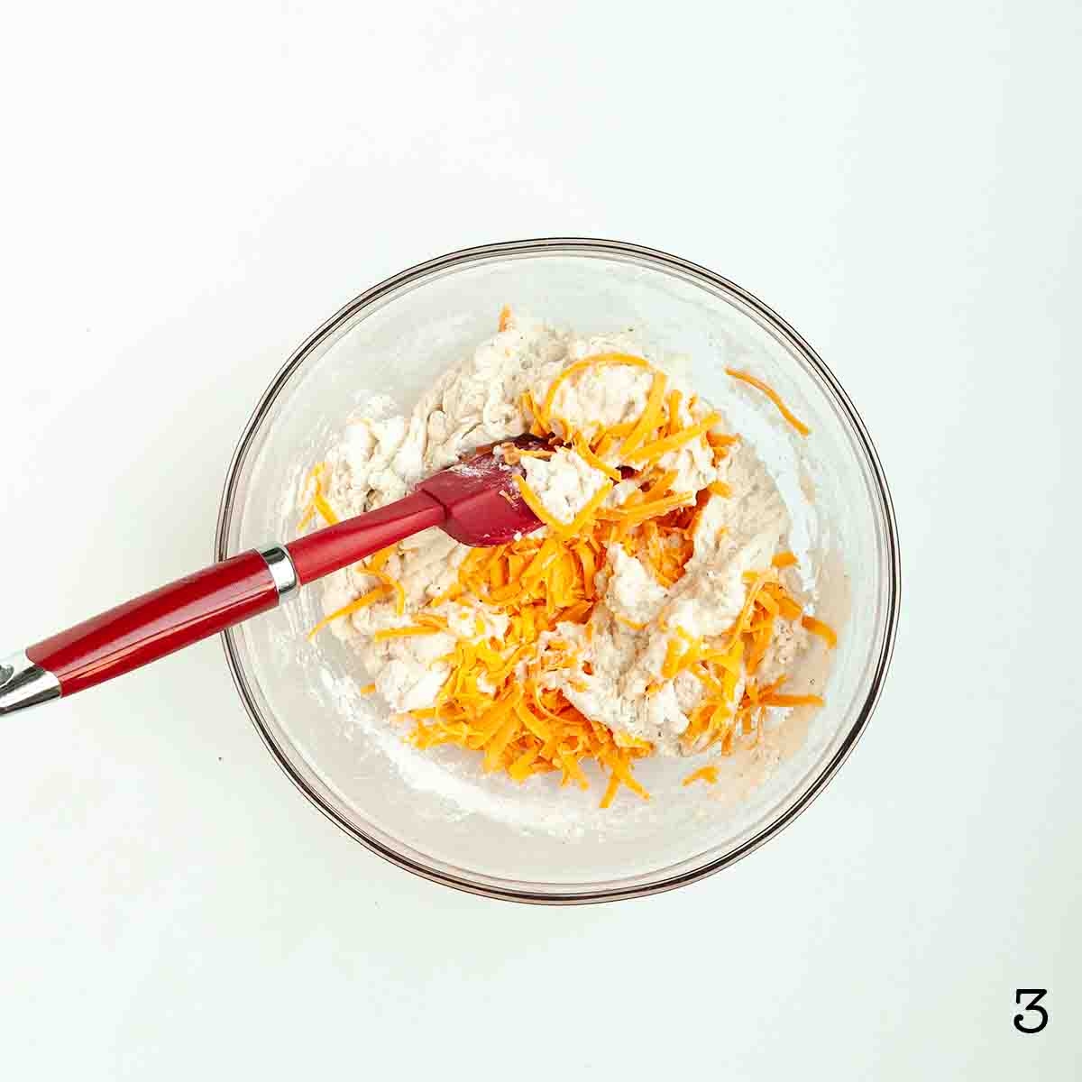 Cheddar cheese being folded into dough.