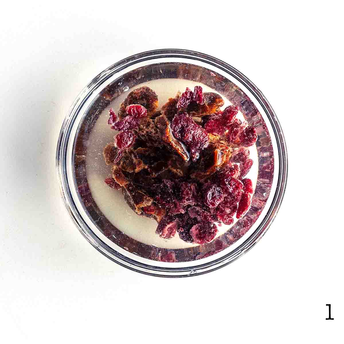 Cranberries, raisins, and dates soaking in a bowl of water.
