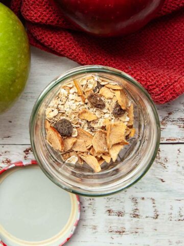 A jar half filled with oats and dried fruits.