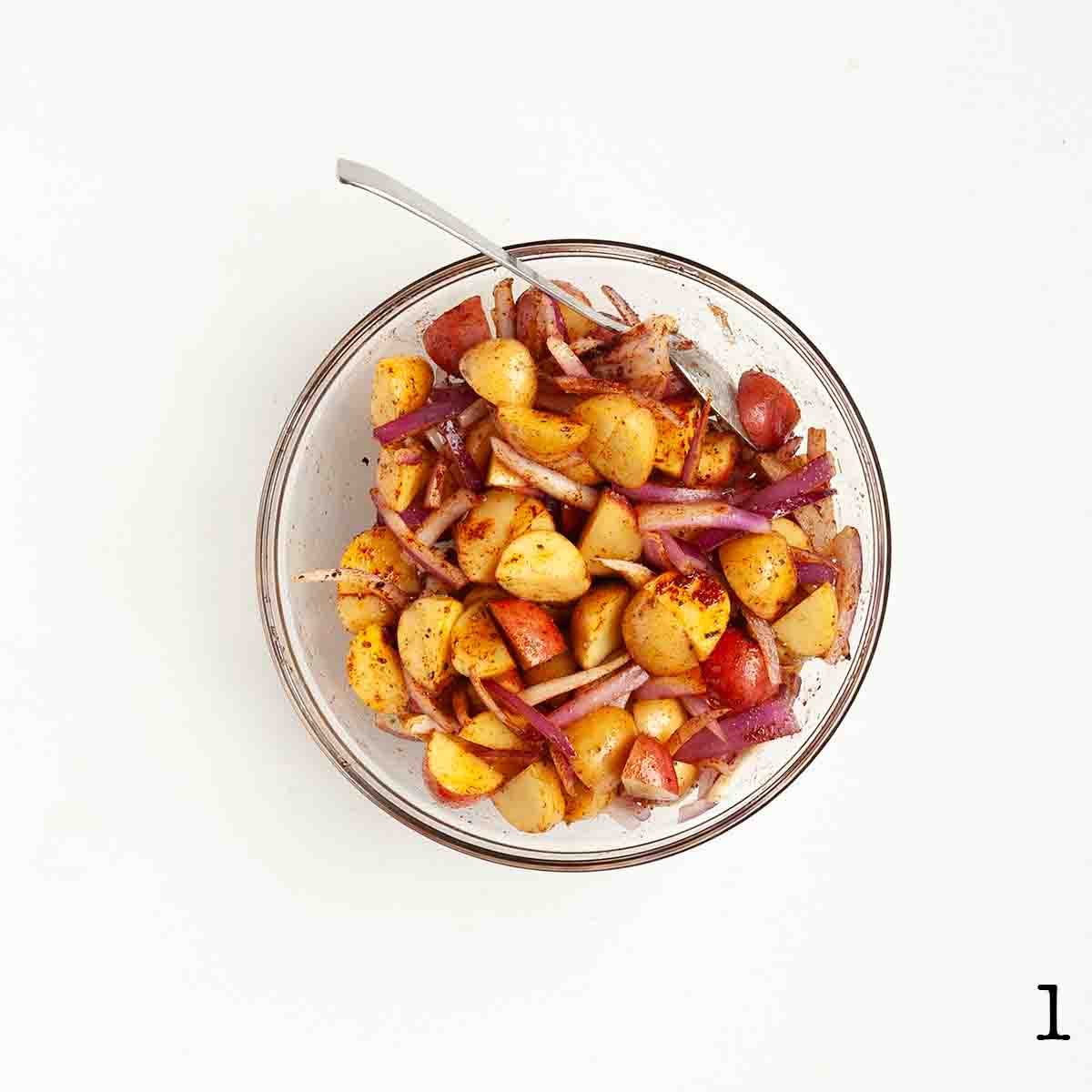 Potatoes and onion mixed in a bowl.