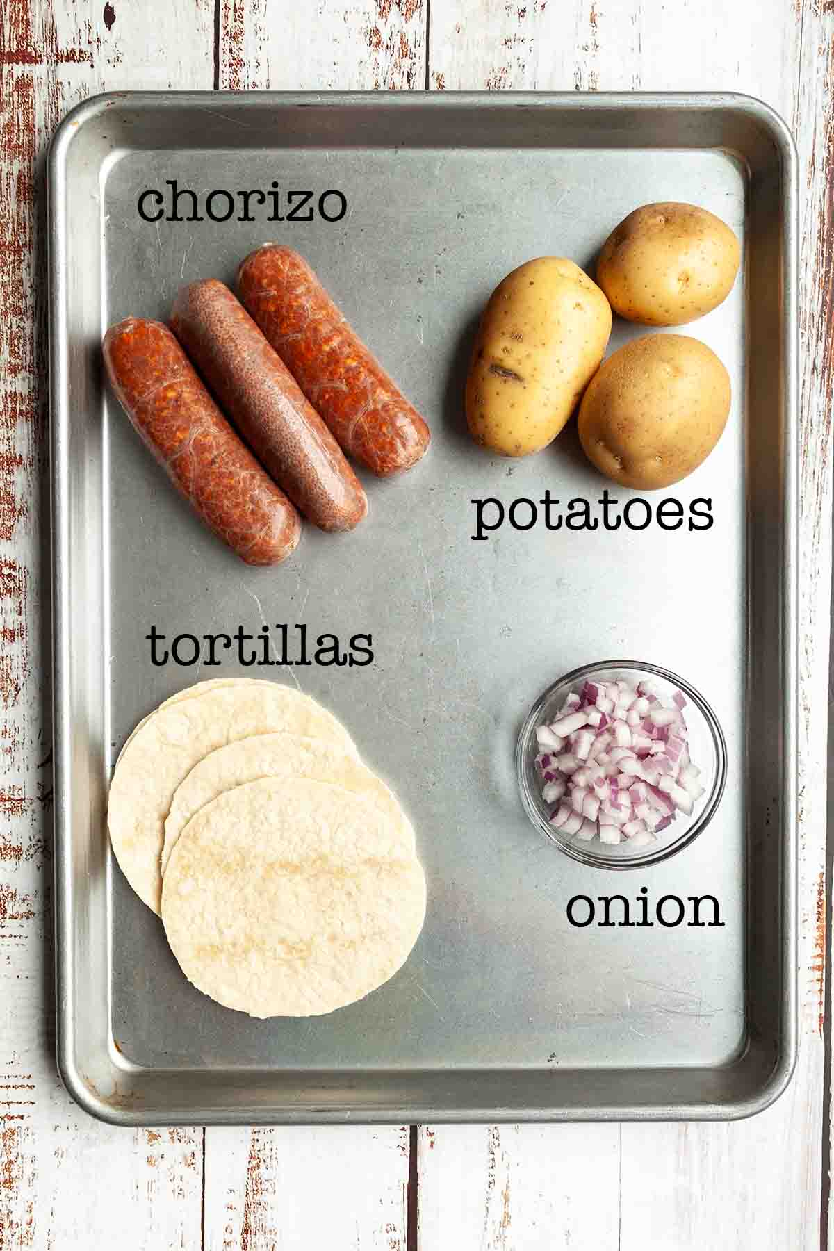 Ingredients for chorizo and potato tacos--chorizo, potatoes, tortillas, and diced red onion.