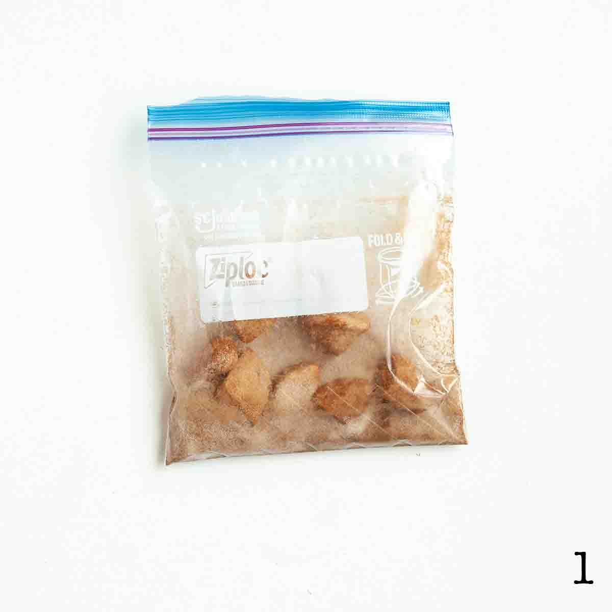 Pieces of biscuit in a bag filled with cinnamon sugar.
