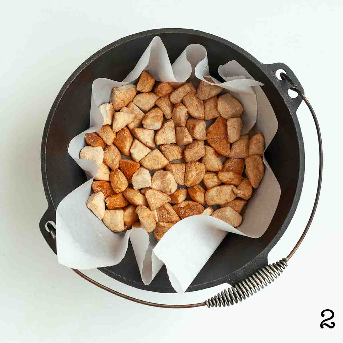 Uncooked biscuit pieces in a parchment-lined Dutch oven.