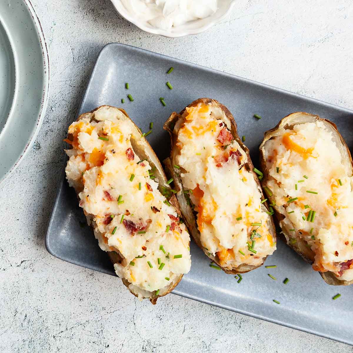 Three grilled twice baked potatoes on a platter.