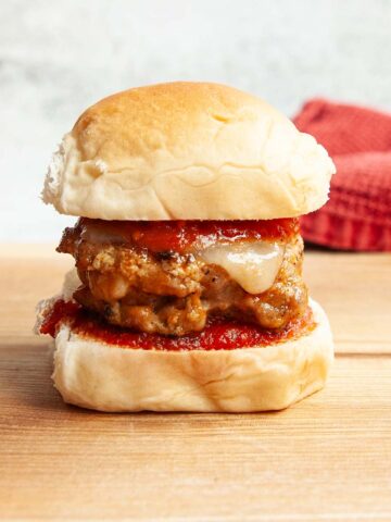 A sausage slider topped with cheese and marinara sauce.