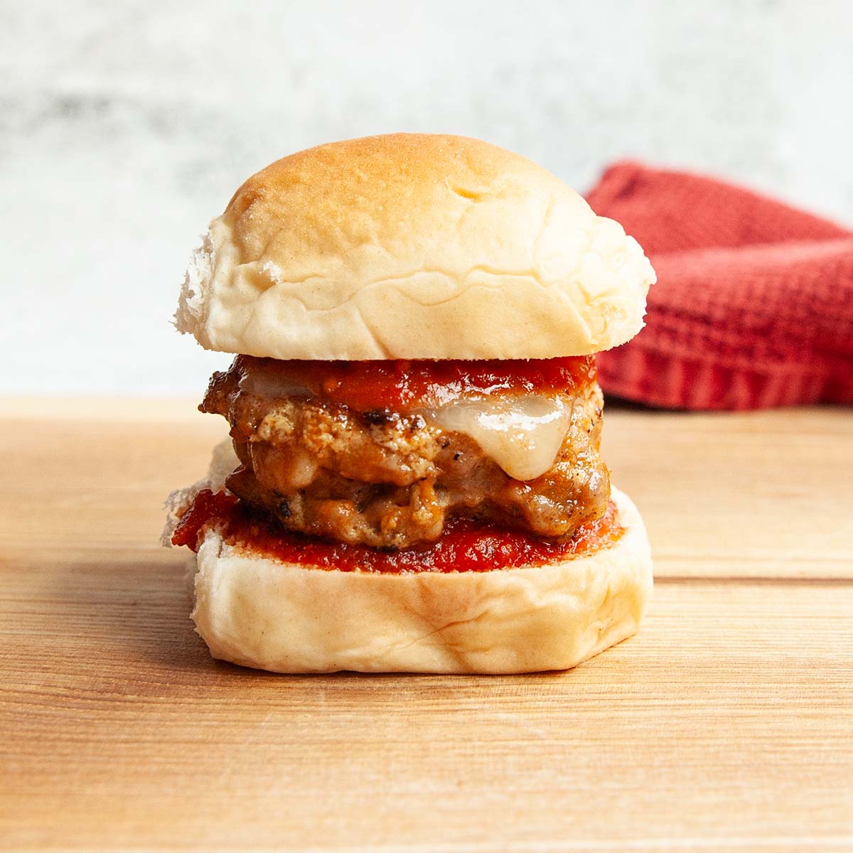 A sausage slider topped with cheese and marinara sauce.
