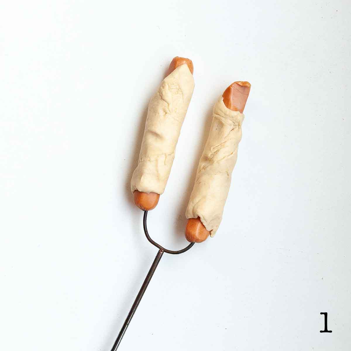 Two hot dogs wrapped in uncooked pastry.