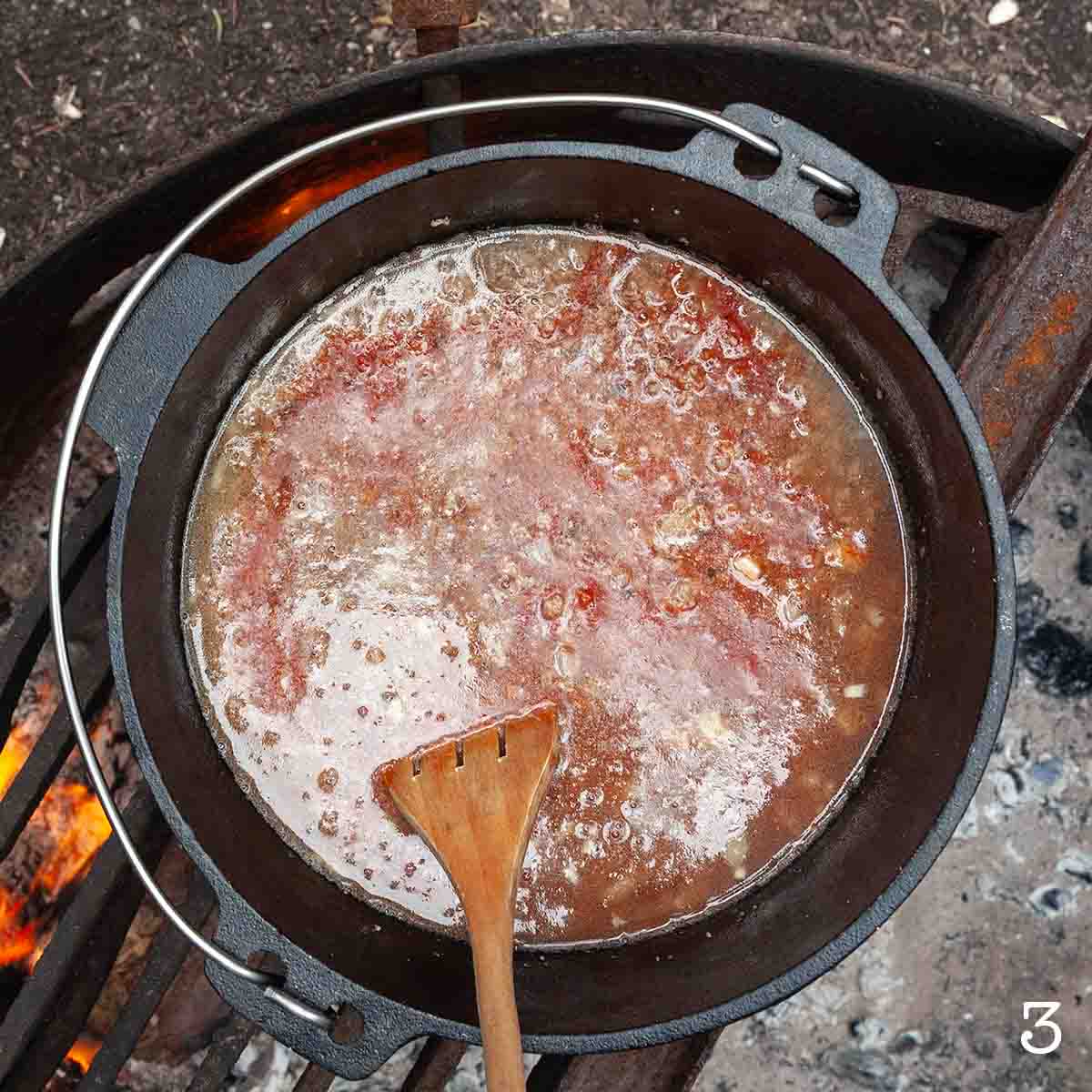 A pot of liquid over a campfire.