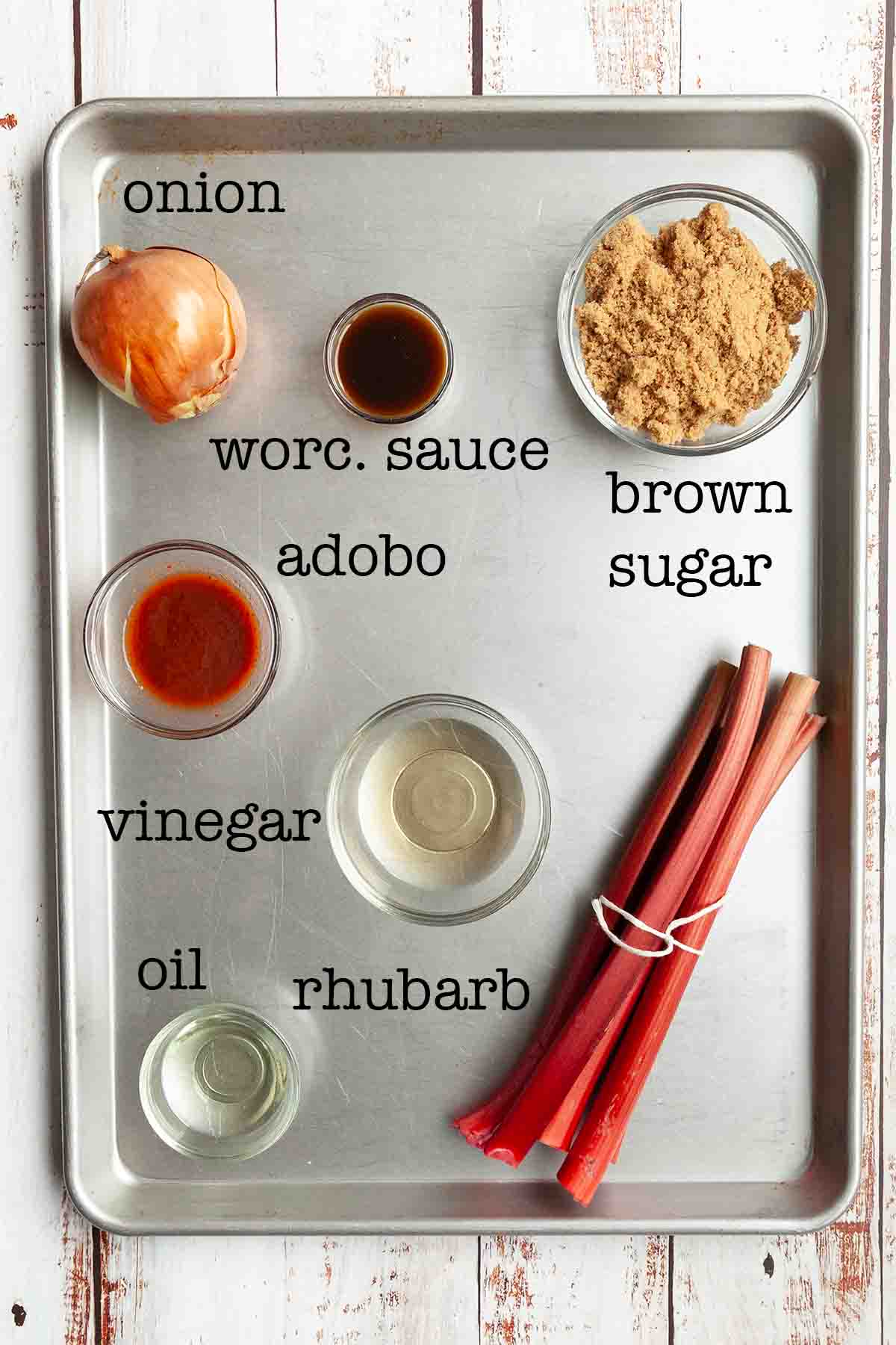 Ingredients for rhubarb bbq sauce--onion, worcestershire sauce, brown sugar, adobo sauce, vinegar, oil, and rhubarb.