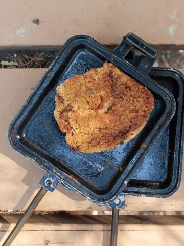 A chocolate chip cookie in a campfire pie iron.