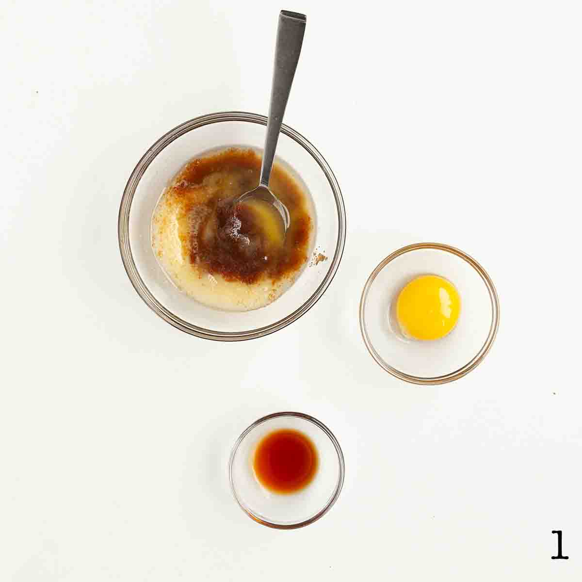 Brown sugar and melted butter in a bowl with an egg yolk and vanilla nearby.
