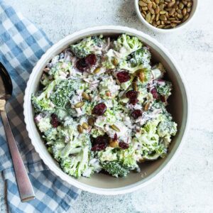 A bowl of broccoli salad with cranberries on top.