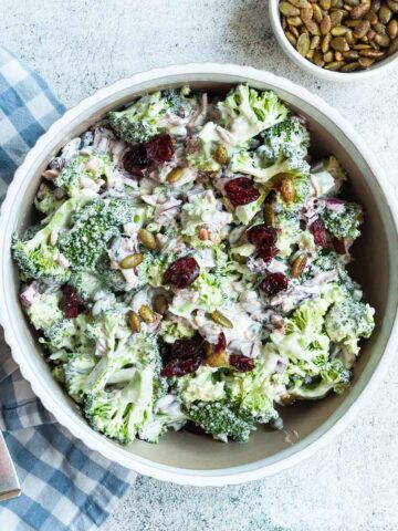 A bowl of broccoli salad with cranberries on top.