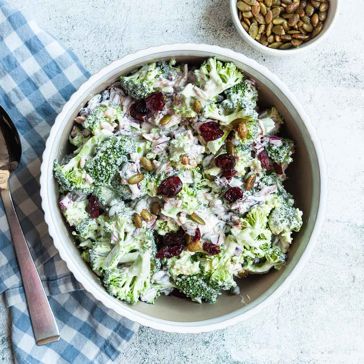 A bowl of broccoli salad with cranberries on top.