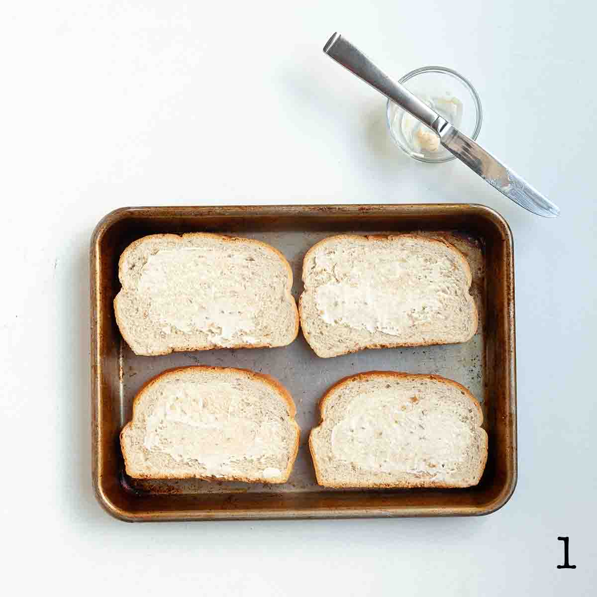 Four slices of bread spread with mayo.