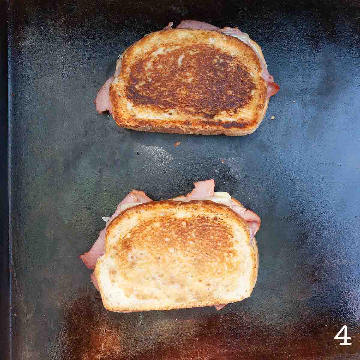 Two reuben sandwiches cooking on a Blackstone griddle.
