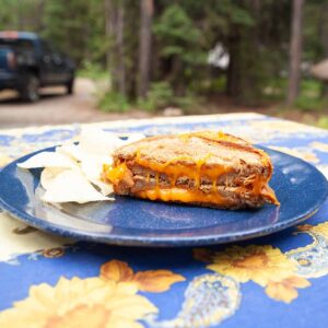 A grilled cheese sandwich cut in half and a handful of potato chips.