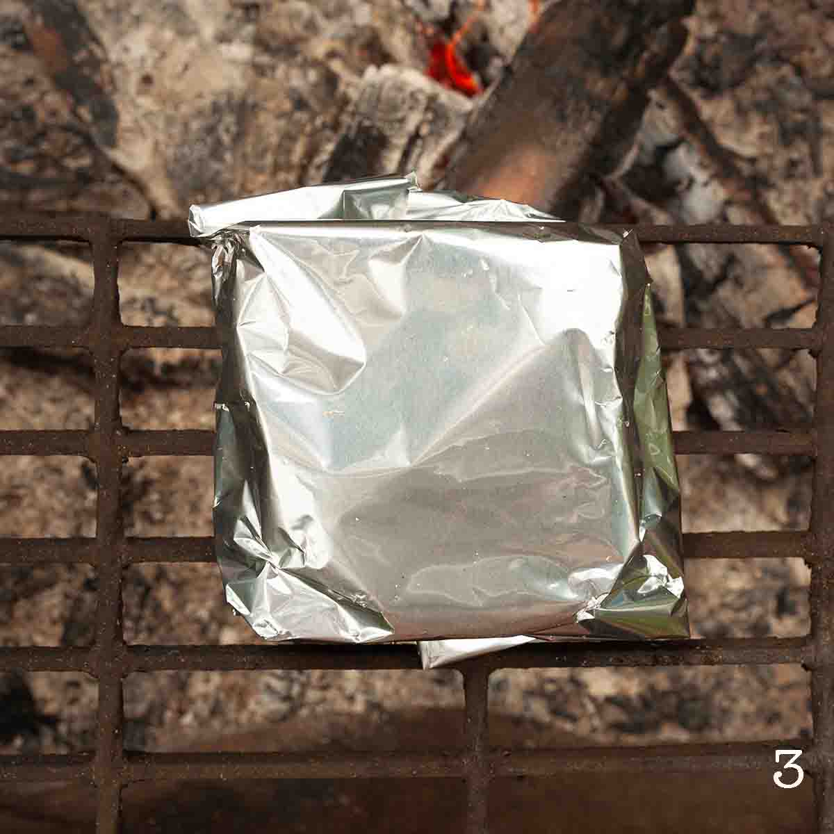 A foil packet over a campfire.