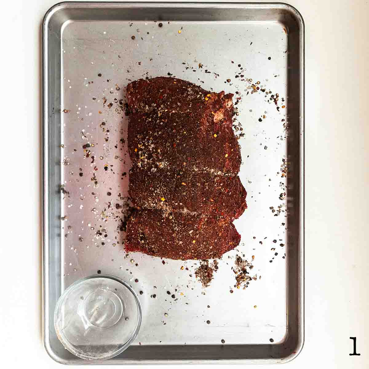 A beef roast covered in BBQ rub.