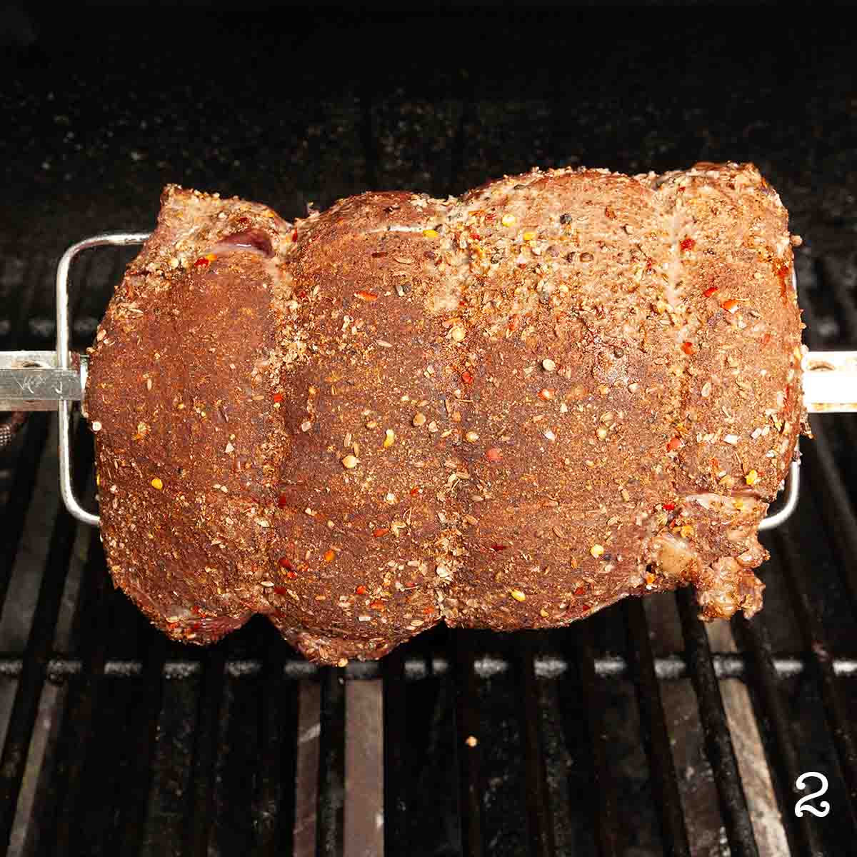 A beef roast on a grill rotisserie.