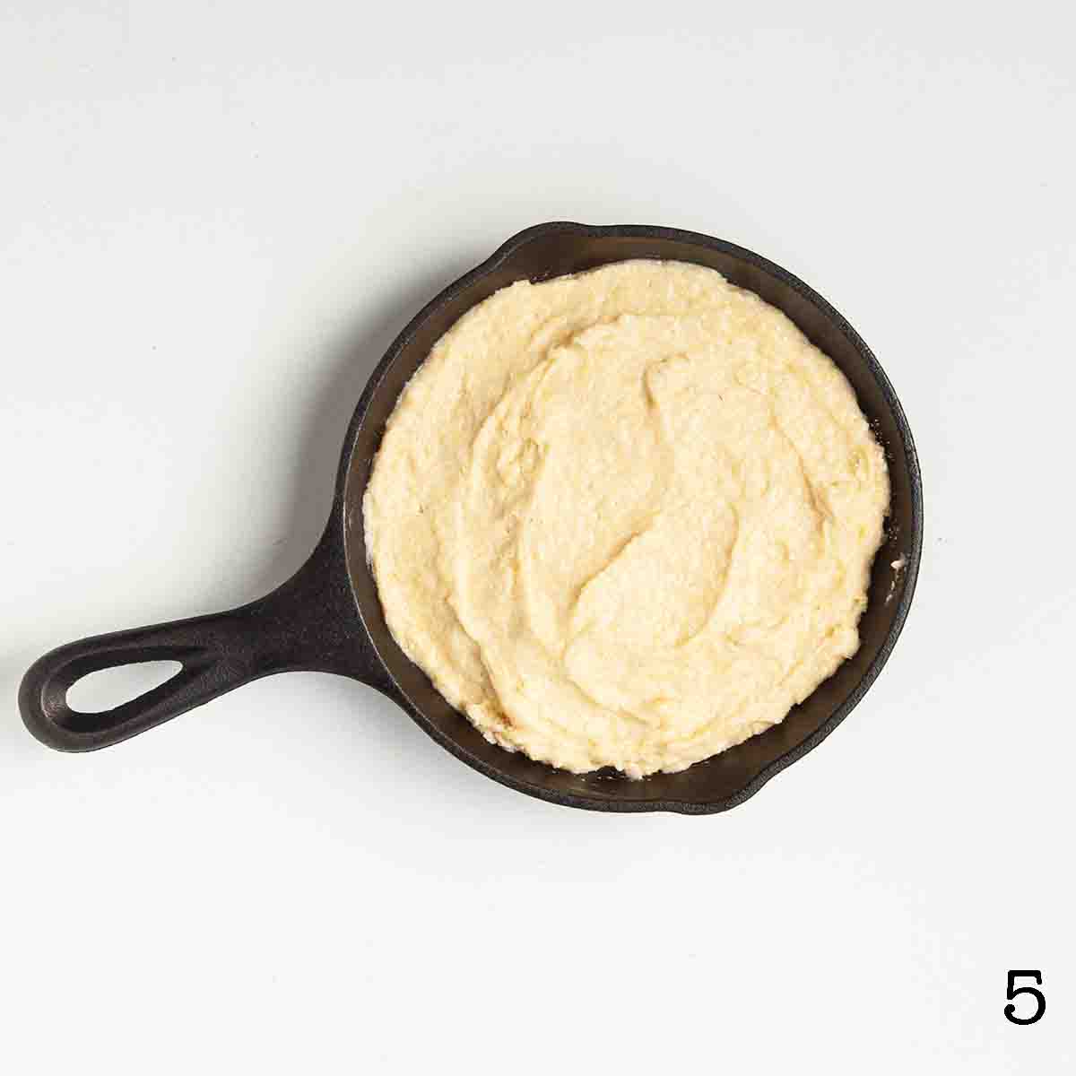 Uncooked cornmeal batter in a cast iron skillet.