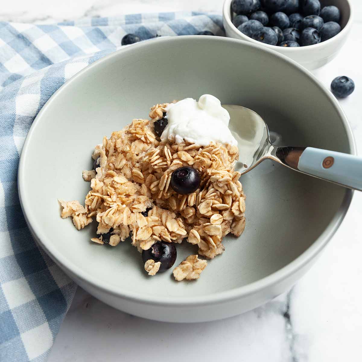 A serving of baked oatmeal with blueberries in a bowl with a dollop of Greek yogurt on top.