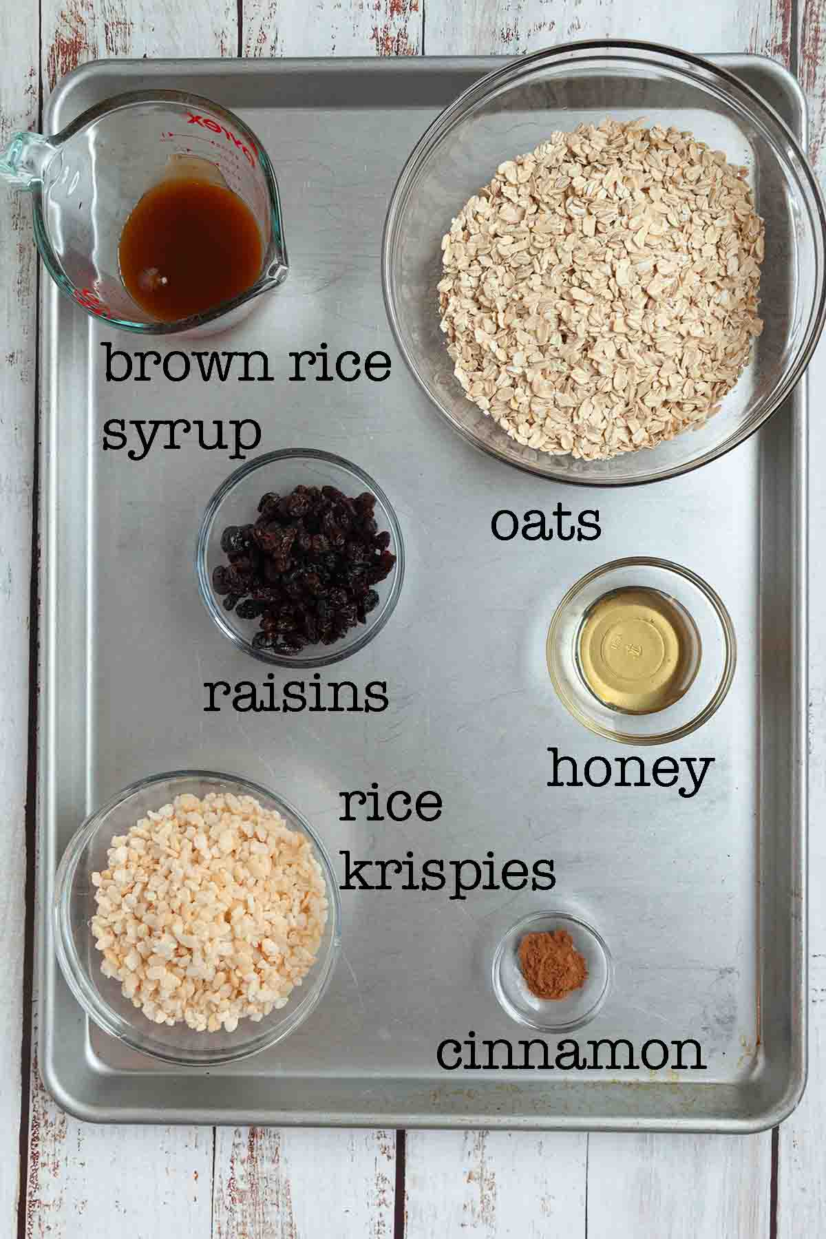 Ingredients for oatmeal raisin bars--brown rice syrup, oats, raisins, honey, rice krispies, and cinnamon.
