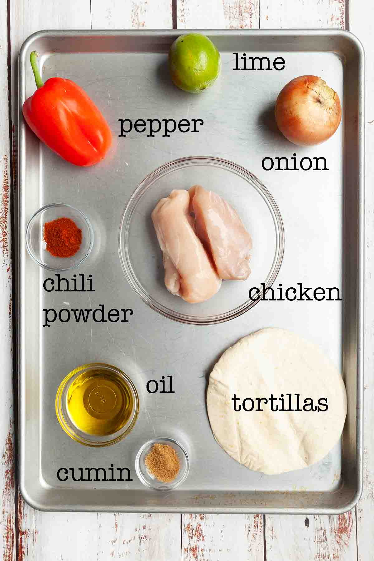 Ingredients for chicken fajitas--lime, onion, pepper, chicken, chili powder, oil, cumin, and. tortillas.