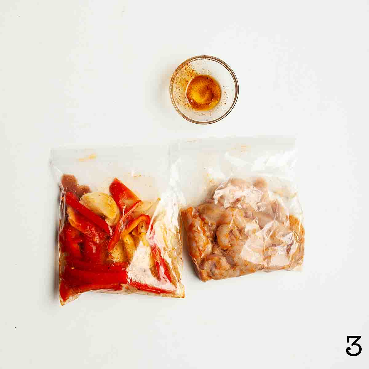 Two bags -- one with strips of raw chicken and one with strips of pepper and onion in marinade.