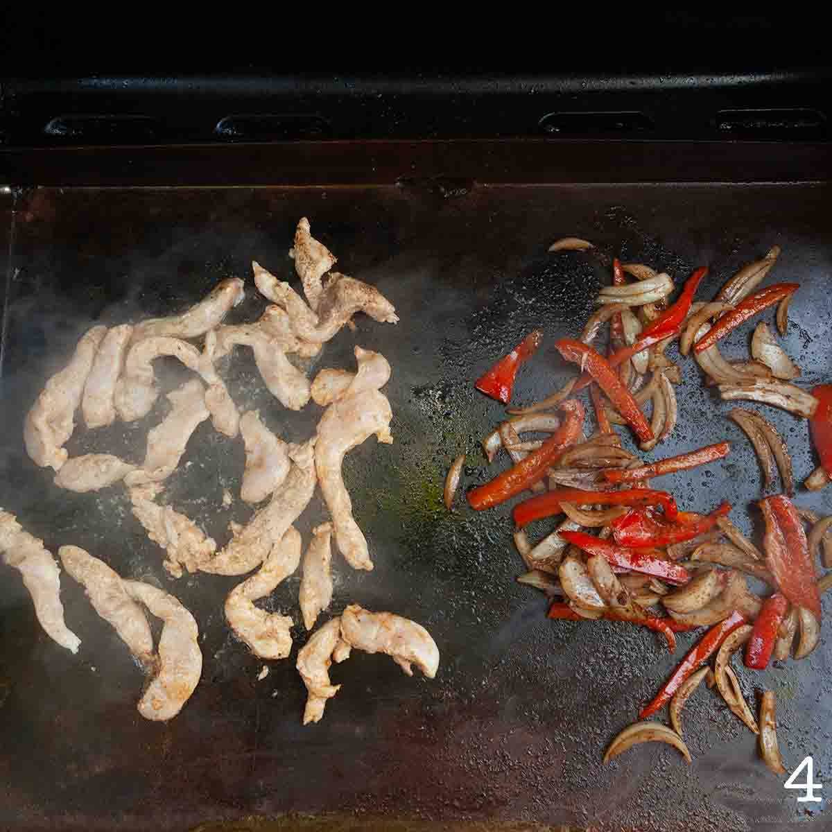 Chicken, pepper, and onion cooking on a griddle.