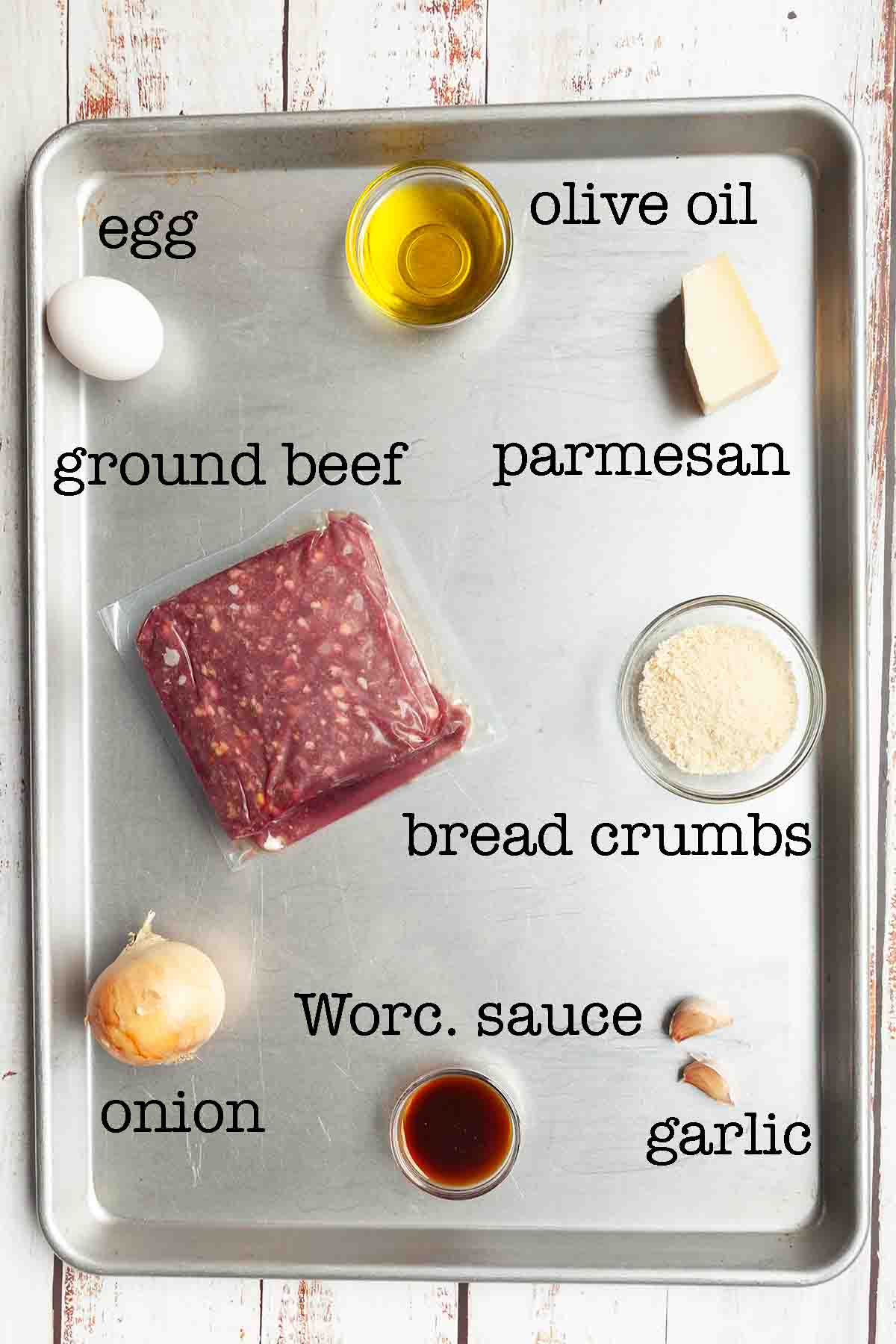 Ingredients for Blackstone meatballs--egg, oil, ground beef, parmesan cheese, bread crumbs, onion, Worcestershire sauce, and garlic.