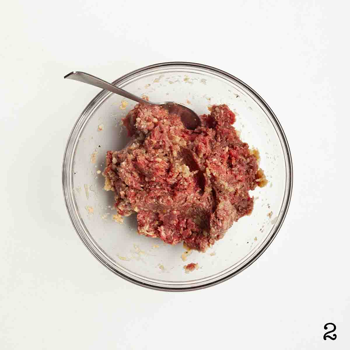 Uncooked meatball mixture in a bowl.