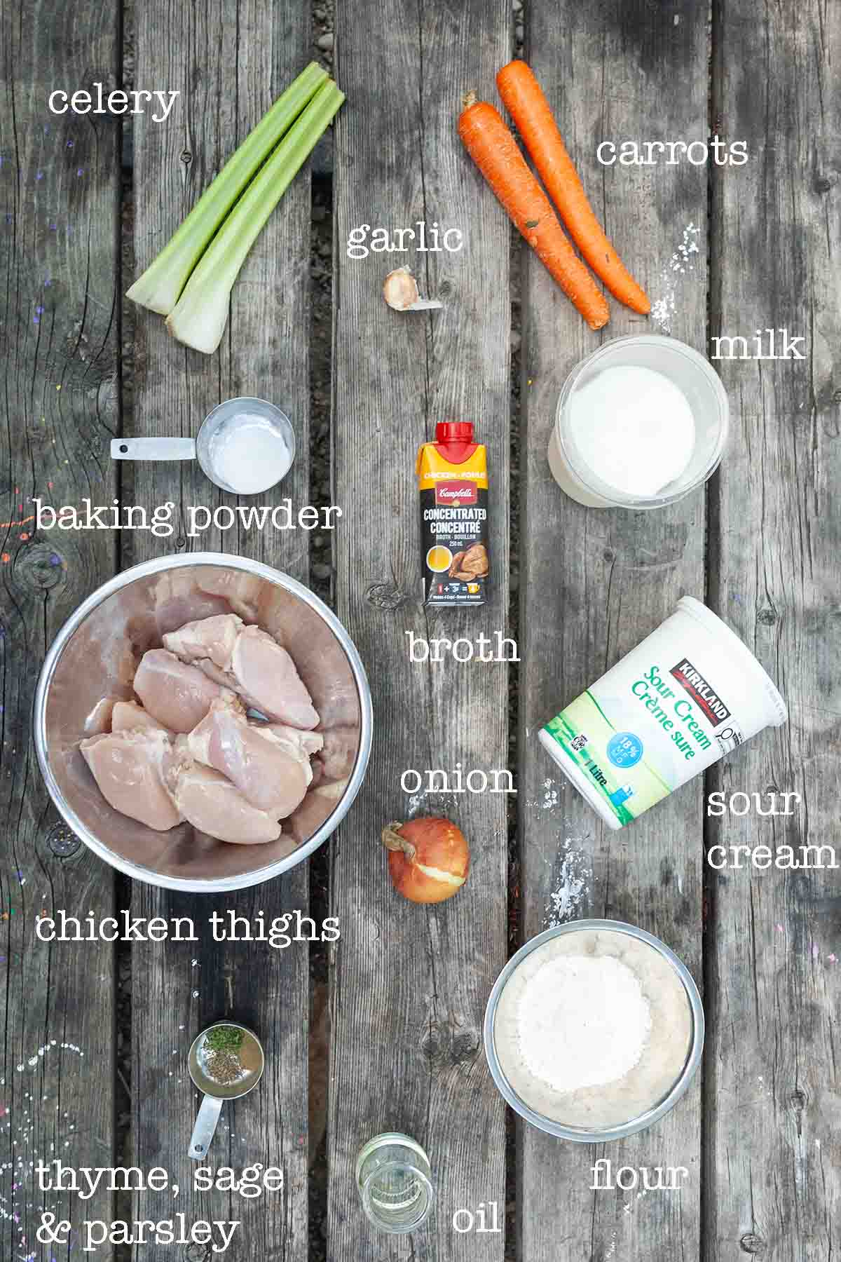 Ingredients for chicken and dumplings--celery, carrots, garlic, baking powder, milk, broth, chicken, onion, sour cream, flour, oil, and spices.