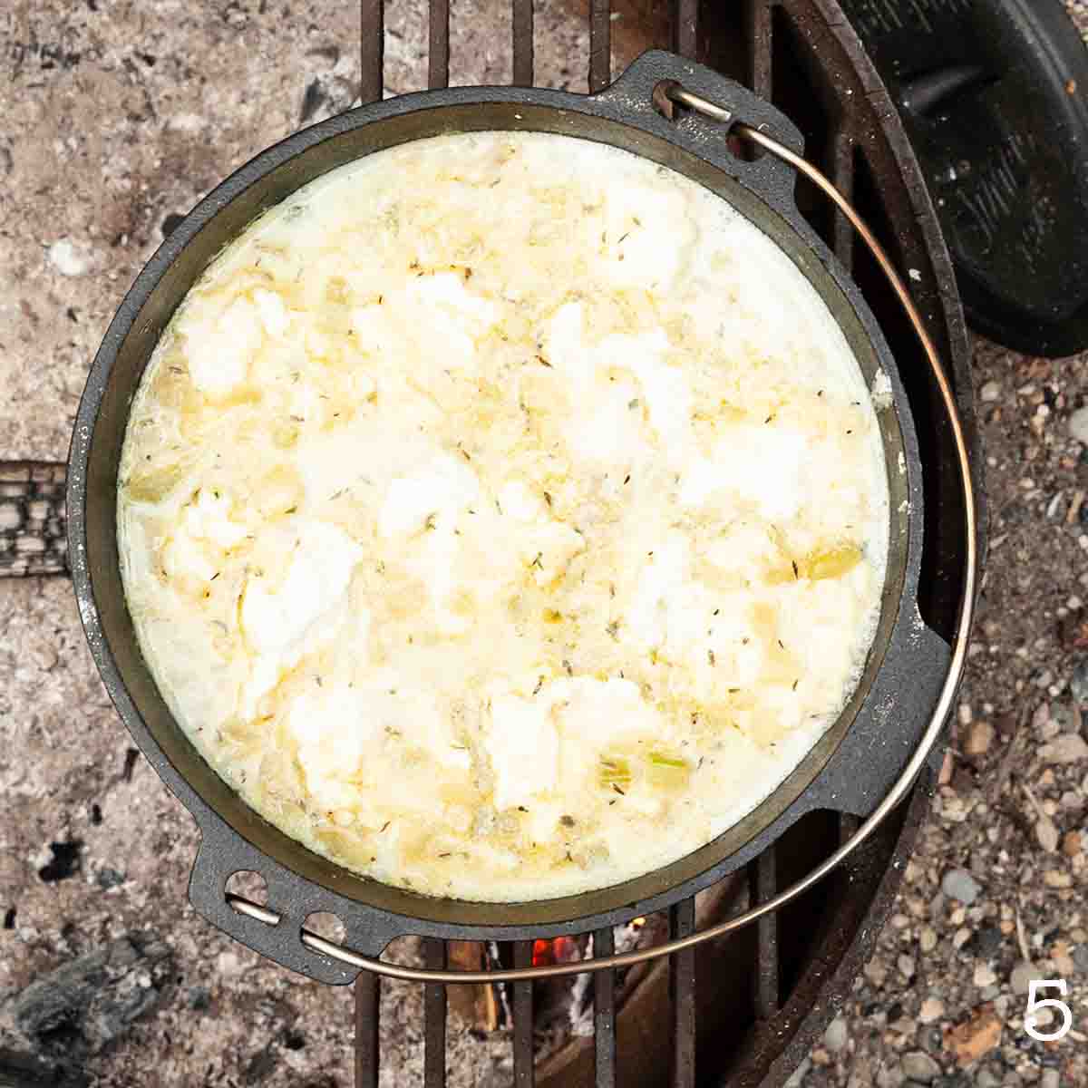 Dumplings in a Dutch oven filled with creamy liquid.