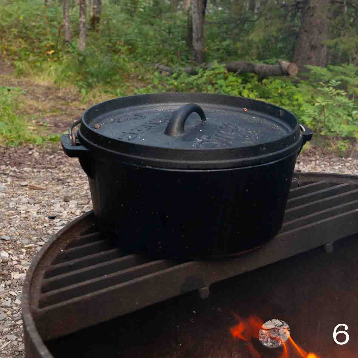 A large Dutch oven set over a campfire.