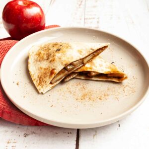 Two pieces of apple pie quesadilla on a plate.