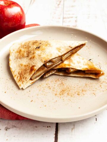 Two pieces of apple pie quesadilla on a plate.