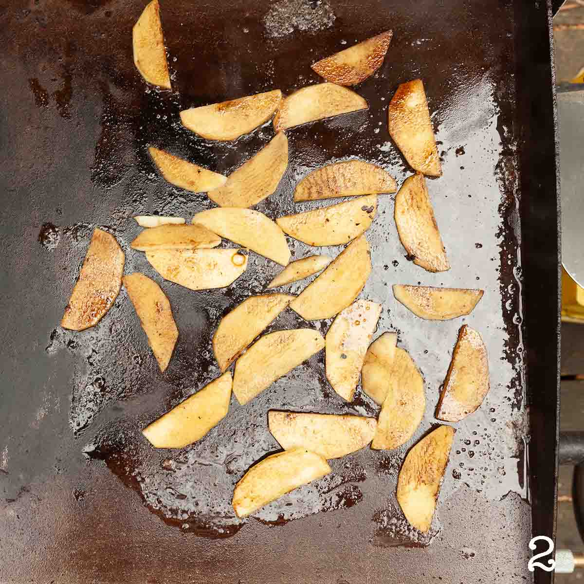 Apple slices cooking on a griddle.