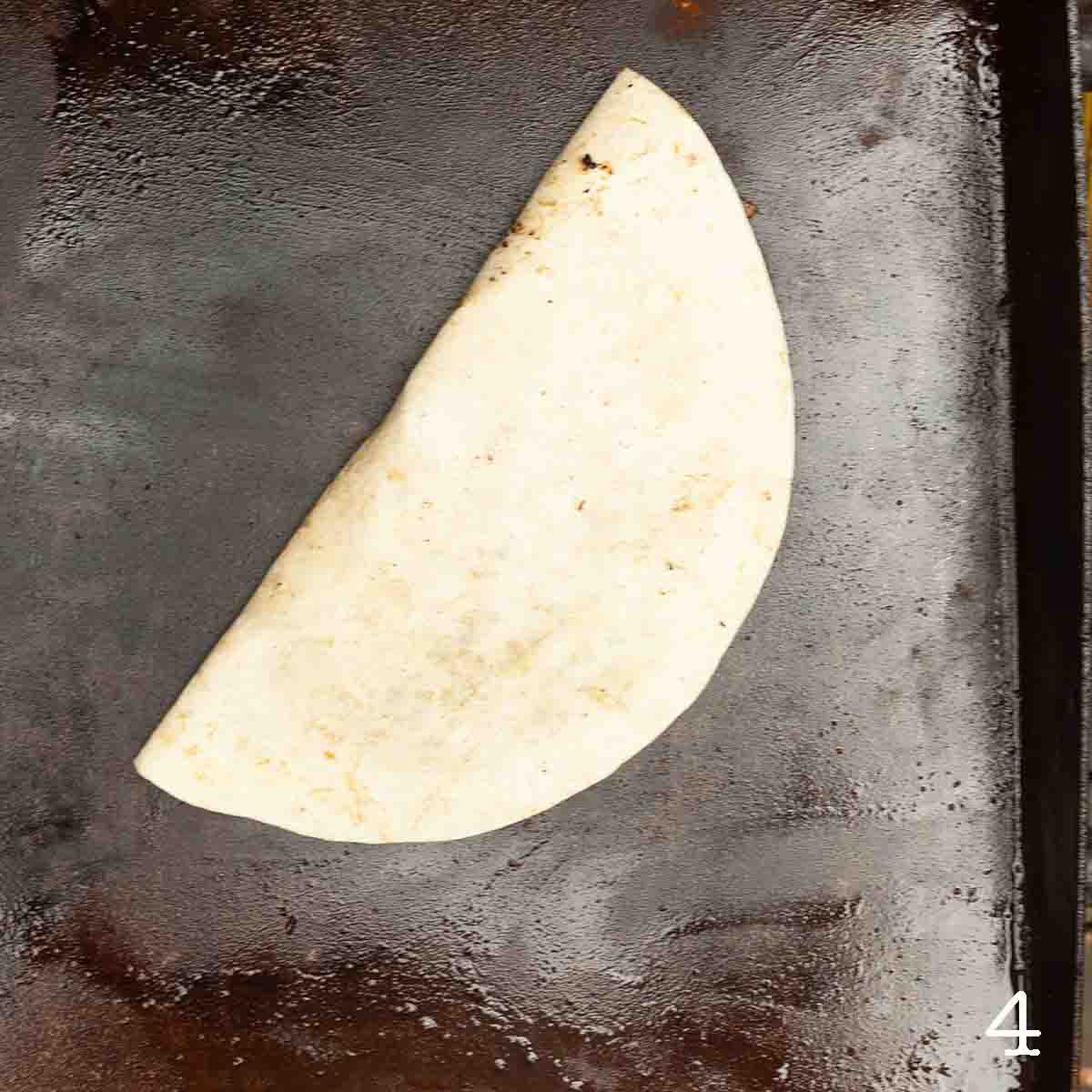A quesadilla cooking on a griddle.